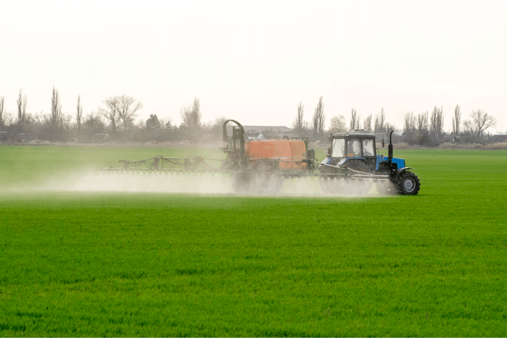 Tractor spraying crops in field.