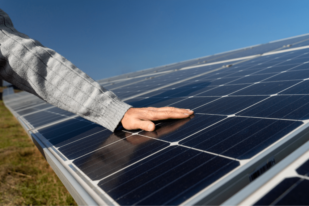 Hand touching solar panel surface.